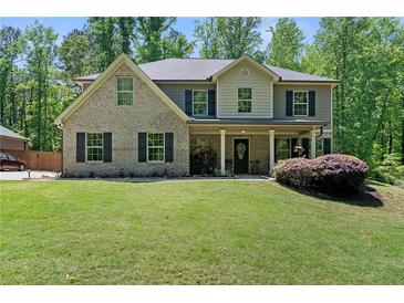 Charming two-story home featuring a covered front porch, well-manicured lawn, and beautiful landscaping at 165 6Th St, Auburn, GA 30011