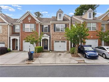 Charming brick townhouse with an attached garage, mature landscaping and front yard parking spaces at 1880 Garbrooke Cv, Lawrenceville, GA 30046