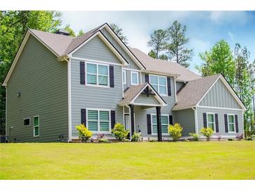Two story home featuring complementary siding, dark shutters, manicured lawn, and mature trees at 445 Boulder Crest Trl, Villa Rica, GA 30180