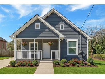 Charming home featuring a stylish gray exterior, covered front porch and well manicured lawn, creating inviting curb appeal at 345 Wellington Sw St, Atlanta, GA 30310