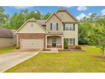 Charming two-story home features a stone-accented facade, well-manicured lawn, and attached two car garage at 2534 Grayton Loop, Villa Rica, GA 30180