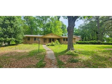 Charming single-story home featuring a brick exterior and a spacious front yard with mature trees and a stone pathway at 2886 The Fontainebleau Sw, Atlanta, GA 30331