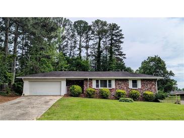 Charming brick home featuring an attached garage and a well-manicured front yard with lush green lawn at 1091 Luther Sw Dr, Mableton, GA 30126