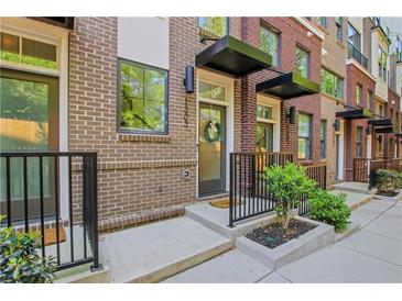 Brick townhome featuring a charming front entry with black awnings, small garden bed and black iron railing at 230 New St # 1303, Decatur, GA 30030