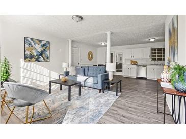 Spacious living room featuring a blue sofa, gray chairs, modern art, and stylish decor at 4781 Brownsville Rd, Powder Springs, GA 30127