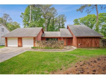 Charming exterior view of home with attached garage, stone accent wall, and lush green lawn at 6134 Silver Spur Dr, Lithonia, GA 30058