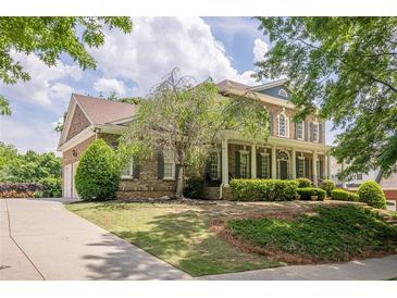Charming two-story brick home boasts a manicured lawn and a welcoming covered front porch at 4891 Tarry Post Ln, Suwanee, GA 30024