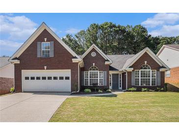 Charming brick home featuring a two-car garage, well-manicured lawn, and classic architectural details at 1180 Chandler Ridge Dr, Lawrenceville, GA 30045