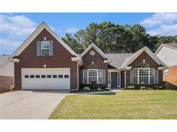 Charming brick home with a well-manicured lawn, attached garage, and beautiful arched windows at 1180 Chandler Ridge Dr, Lawrenceville, GA 30045