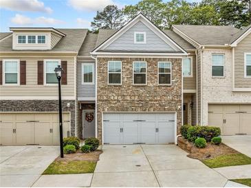 Charming townhome featuring a brick facade, two-car garage, and manicured landscaping at 2142 Arnage Dr, Lithonia, GA 30058