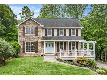 Charming two-story home with a stone facade and a welcoming front porch, nestled among lush trees and landscaping at 4754 Kelley Se Ct, Mableton, GA 30126