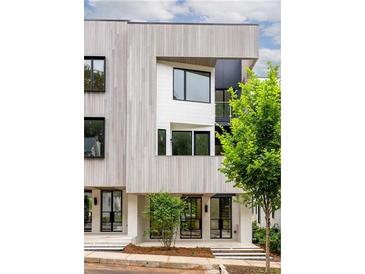 Modern three-story townhouse with clean lines and a light-colored facade, accented by dark window frames and lush greenery at 11548 Serenbe Ln, Chattahoochee Hills, GA 30268