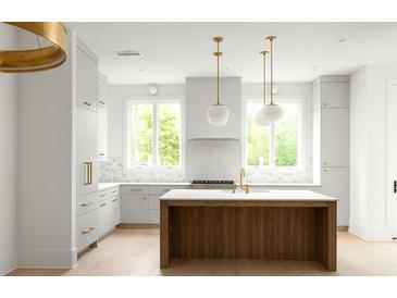 Modern kitchen featuring a wood island, white cabinets, stainless steel appliances, and stylish pendant lighting at 11548 Serenbe Ln, Chattahoochee Hills, GA 30268