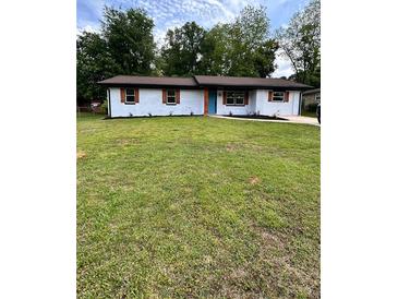 Charming single-story home with freshly painted white brick, a vibrant blue door, and a well-manicured green lawn at 4074 Green Hawk Trl, Decatur, GA 30035