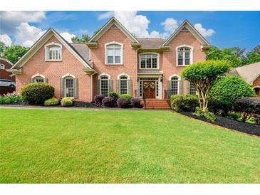 Beautiful brick home featuring a lush lawn, mature landscaping, and an inviting entrance at 1430 Hampton Hill Dr, Alpharetta, GA 30022