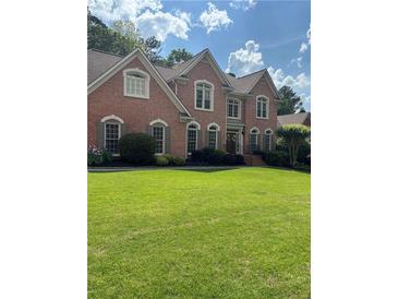 Charming two-story brick home with a large manicured front lawn and classic architectural details at 1430 Hampton Hill Dr, Alpharetta, GA 30022