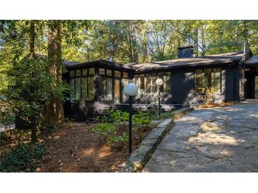 Stunning exterior of a black painted brick home with a private driveway and lush landscaping at 922 Barton Woods Ne Rd, Atlanta, GA 30307
