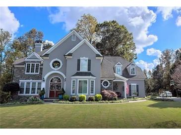Elegant two-story home with stone and stucco exterior, manicured lawn, and mature trees at 2645 Preston Ridge Ln, Dacula, GA 30019