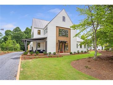 Stunning two-story modern farmhouse with metal roof and manicured lawn on a sunny day at 12520 Celestine Way, Milton, GA 30075