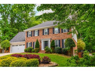 Beautiful two-story brick home with lush landscaping and mature trees providing ample shade at 615 Woodwork Way, Roswell, GA 30076