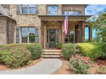 Charming front door with an American flag, stone stairs and beautiful landscaping in this stunning, inviting home at 7045 Parrish Way, Cumming, GA 30040