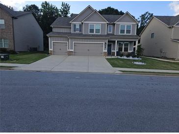 Charming two-story home with a well-maintained lawn and a spacious three car garage at 221 Eleanora Way, Loganville, GA 30052