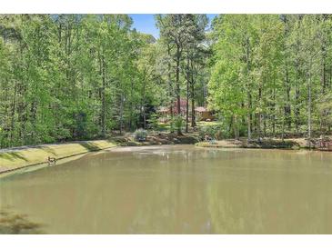 Beautiful view of home behind a pond with mature trees and lush greenery surrounding the property at 337 Andrew Bailey Rd, Sharpsburg, GA 30277