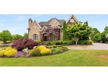 Beautiful brick home featuring professionally landscaped front yard with mature trees and colorful flower beds at 2855 Drayton Hall Dr, Buford, GA 30519