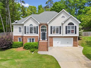 Charming two-story home featuring a brick and stucco facade, black shutters, and a well-manicured lawn at 47 Centerport Dr, White, GA 30184