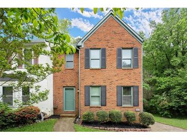 Charming brick front home with a manicured lawn, lush greenery and complemented by dark shutters at 855 Cedar Bluff Ct, Marietta, GA 30062