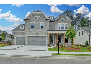 Beautiful two-story home with gray brick, three-car garage, and craftsman style front porch at 11305 Knollwood Bend, Johns Creek, GA 30097
