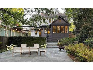 Inviting backyard featuring a stone patio, dining set, fire pit, and lush landscaping, perfect for outdoor entertaining at 872 Euclid Ne Ave, Atlanta, GA 30307