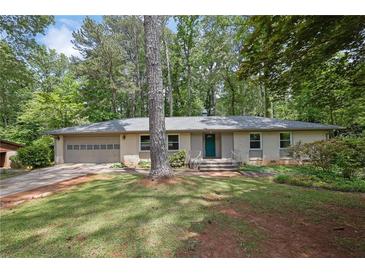 Charming brick home with a two-car garage, lush greenery, and a welcoming front entrance at 4420 Lake Breeze Dr, Stone Mountain, GA 30083