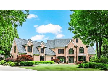 Impressive brick home featuring manicured landscaping, a large lawn, and architectural roof lines at 6515 Ashbourne Ct, Suwanee, GA 30024