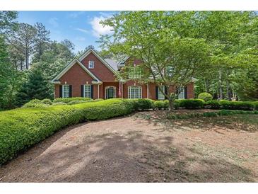 Charming two-story brick home featuring manicured landscaping, mature trees and lush greenery at 4810 Duncans Lake Dr, Buford, GA 30519