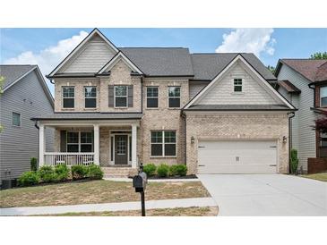 Beautiful two-story brick home featuring a well-manicured lawn, covered porch, and attached two-car garage at 2927 Dolostone Way, Dacula, GA 30019