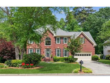 Charming two-story brick home featuring lush landscaping, a well-manicured lawn, and an attached two-car garage at 4140 Lansfaire Ter, Suwanee, GA 30024