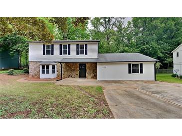 Charming split-level home featuring stone accents, a well-manicured lawn, and a classic, inviting facade at 5429 Martins Crossing Rd, Stone Mountain, GA 30088