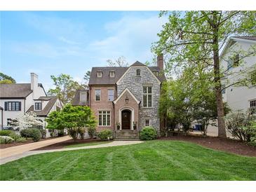Charming brick and stone home with manicured lawn, complemented by mature trees under a partly cloudy sky at 603 E Paces Ferry Ne Rd, Atlanta, GA 30305