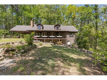 Charming log home with a welcoming front porch, nestled among lush trees and beautiful landscaping at 2377 Pine Mountain Rd, Kennesaw, GA 30152