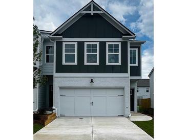 Charming two-story home featuring a two-car garage and a modern, dark-green paneled facade at 1956 Asher Ln # 51, Conyers, GA 30013