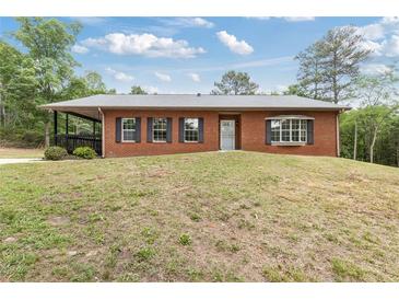 Charming brick home featuring a covered porch and a well-maintained front yard at 3881 Moore Rd, Ellenwood, GA 30294