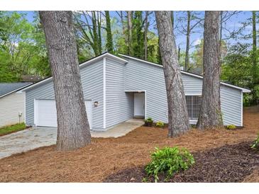 Charming home featuring light gray siding, a one-car garage, and beautifully landscaped front yard at 1360 Terramount Dr, Roswell, GA 30076
