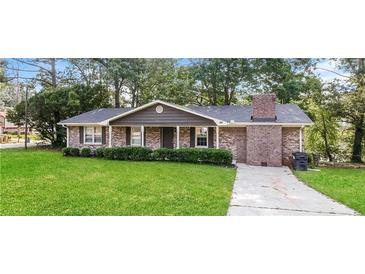 Charming brick home featuring a well-manicured lawn, mature trees, and a classic brick chimney at 2914 Landmark Se Dr, Conyers, GA 30094