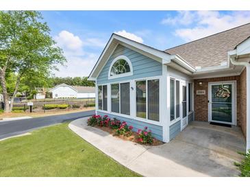 Charming home featuring an enclosed sunroom, flower beds and a well-manicured lawn at 15104 Harvest Ridge Ln, Alpharetta, GA 30022