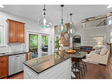 Open kitchen with granite counters, stainless appliances, and island seating overlooking the living area at 6250 Vista Crossing Way, Cumming, GA 30028