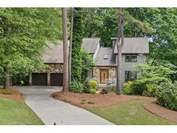 Charming exterior featuring stone accents, neutral siding, well-maintained landscaping, and an attached two-car garage at 1498 Camp Point Ne Ct, Roswell, GA 30075