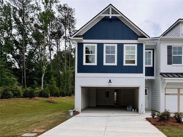 Modern townhome featuring a two-car garage, blue accents, and manicured lawn at 1964 Asher Ln # 47, Conyers, GA 30013