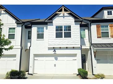 Charming townhome with a white brick exterior, garage, black accents, and well-manicured landscaping at 340 Auburn Valley Way, Auburn, GA 30011