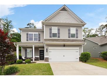 Charming two-story home featuring a well-manicured lawn, gray siding and shutters and a two-car garage at 129 Prominence Ct, Canton, GA 30114